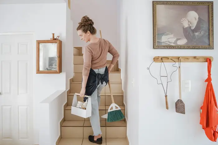 A cleaner carrying supplies up a staircase