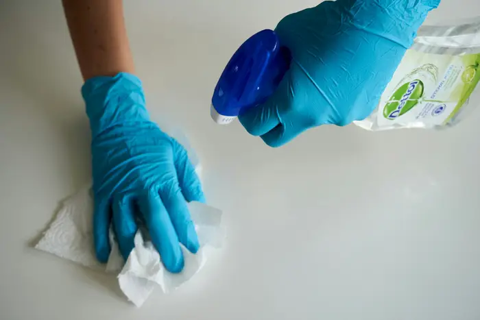 A gloved hand wiping a white counter