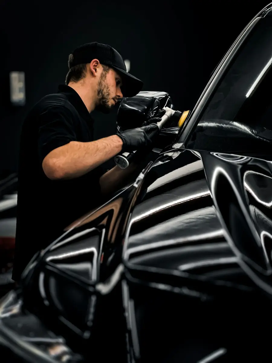 A detailer polishing the paint of a black car